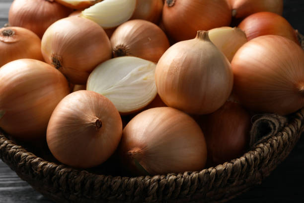 istock Whole and cut onions on black wooden table, closeup 1822764045