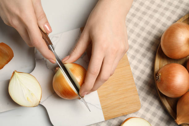 istock Woman cutting ripe onion at white marble table, top view 1822764364