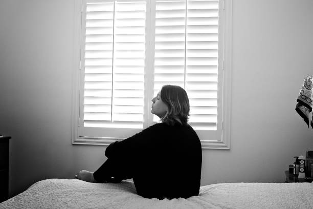 Woman sitting on bed looking upwards