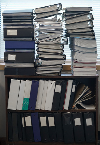 stacks of files, folders and paperwork on bookshelf in the office