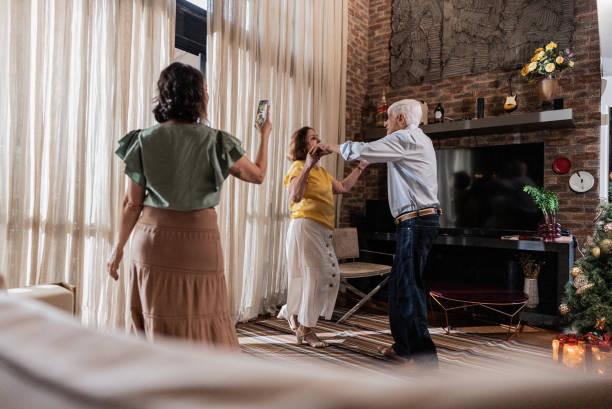 Mature woman filming parents dancing during Christmas time at home Mature woman filming parents dancing during christmas time at home father daughter 80s stock pictures, royalty-free photos & images