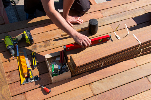 Ipe wood terrace deck construction, view of carpenter hands with a spirit level and woodworking tools while installing a deck, tropical hardwood decking