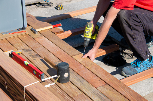 Hardwood terrace deck construction - hardworking man installing exotic ipe wood decking lumber boards