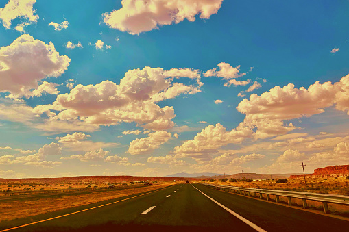 Image of a major roadway in the American Southwest from the perspective of someone in the center, looking ahead until the road meets the horizon.