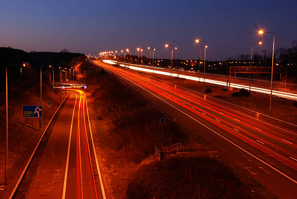 Image of car lights trailing along the highway Trails of light left by vehicles traveling at night on a motorway in England UK. m2 machine gun photos stock pictures, royalty-free photos & images
