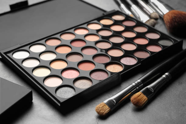istock Beautiful eye shadow palette and brushes on dark grey table 1822836703