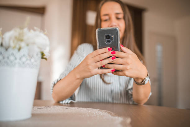 istock Woman using smartphone while resting in hotel room sitting at table, the focus is on the mobile phone 1822869570