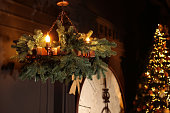 Vintage chandelier decorated with fir branches on ceiling and Christmas tree in room