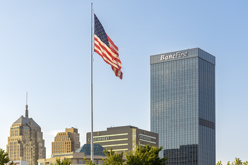 Oklahoma City, USA - October 25th, 2023: View of the modern BancFirst bank tower and flag of United States of America.