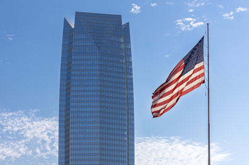Oklahoma City, USA - October 25th, 2023: Devon Energy Center corporate skyscraper in downtown and flag of United states of America.