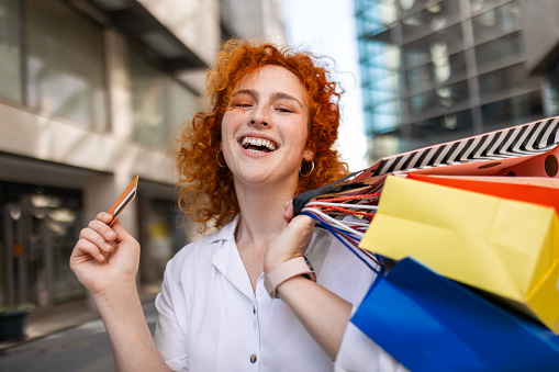 Redhead woman returning from a shopping mall holding shopping bags looking at camera