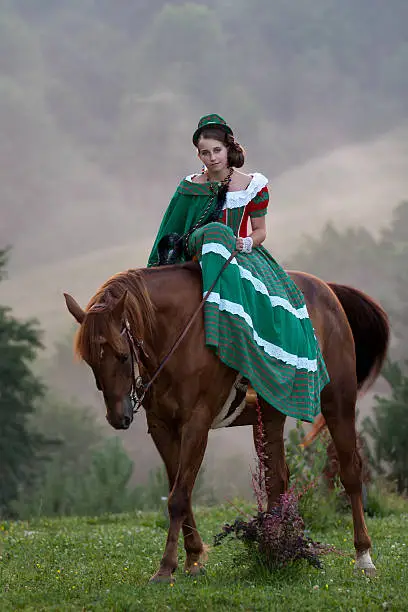 Girl riding equestrian classicism dress in fog