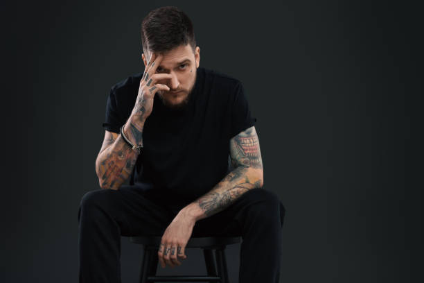 istock Handsome hipster man posing on chair against black background. Space for text 1822917617