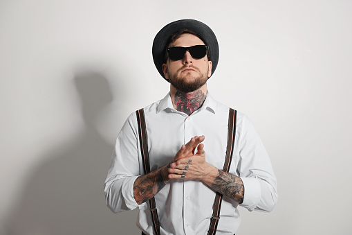 Handsome hipster man wearing stylish sunglasses on light grey background