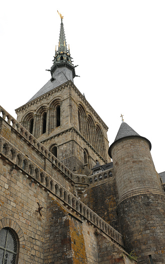 view from below of bell tower with the golden statue of the archangel Michael in the Mont Saint Michel Abbey in northern France
