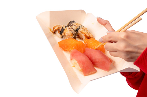 Food delivery. A box with sushi rolls in woman hands isolated on a white background.