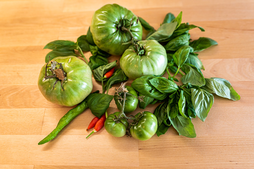 Fresh Green Tomato, Basil and Chili Pepper on Wooden Table
