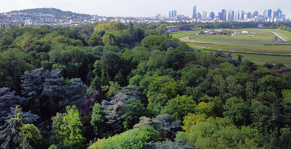Amazing drone point of view on Park of Edmond  de Rothschild, part of Boise de Boulogne with field for horse racing and  in distance skyscrapers of La Defense business district  (on other side of Seine river , river not visible) - fantastic Paris  in Mid May