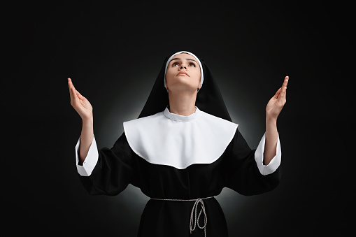 Nun praying to God on black background