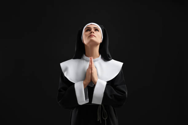 istock Nun with clasped hands praying to God on black background 1823060493