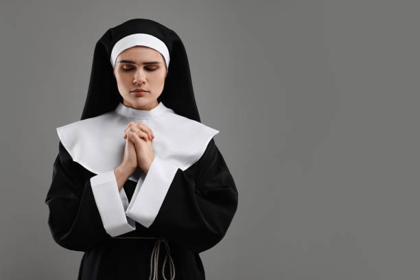 istock Nun with clasped hands praying to God on grey background. Space for text 1823060496