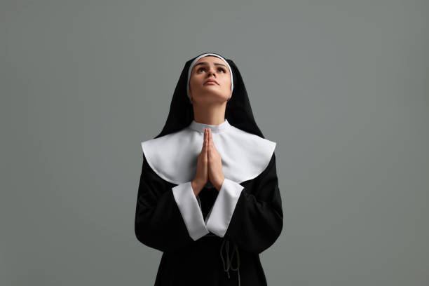 istock Nun with clasped hands praying to God on grey background 1823061015