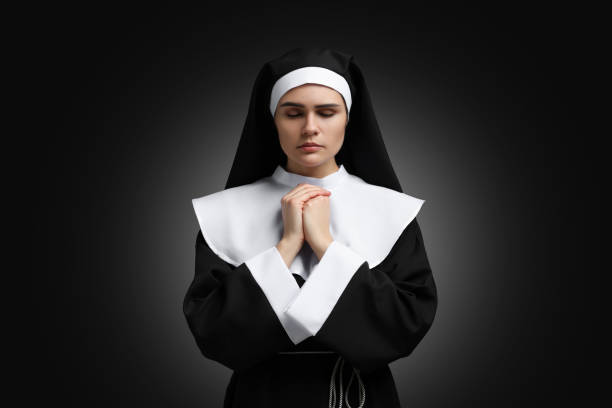 istock Nun with clasped hands praying to God on black background 1823061022