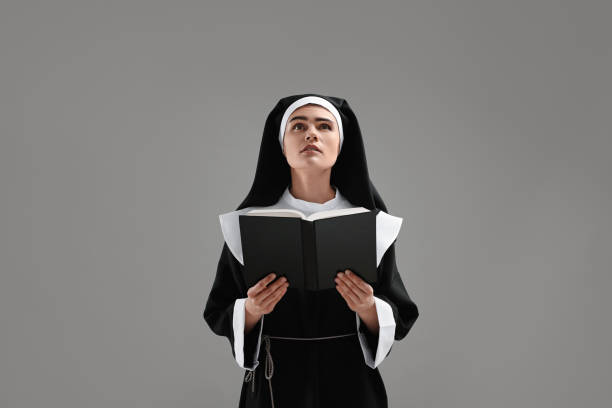 istock Nun with Bible praying to God on grey background 1823061541