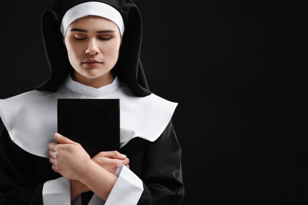 istock Nun with Bible on black background, space for text 1823062078