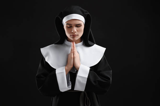 istock Nun with clasped hands praying to God on black background 1823062082
