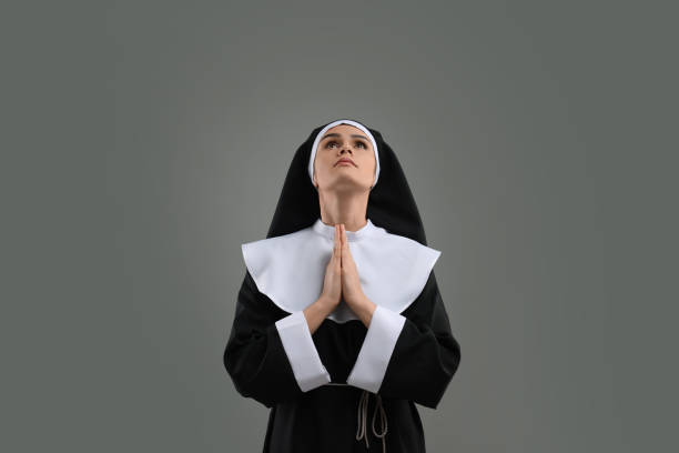 istock Nun with clasped hands praying to God on grey background 1823062280