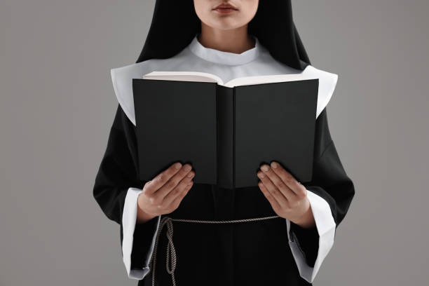 istock Nun reading Bible on grey background, closeup 1823062600