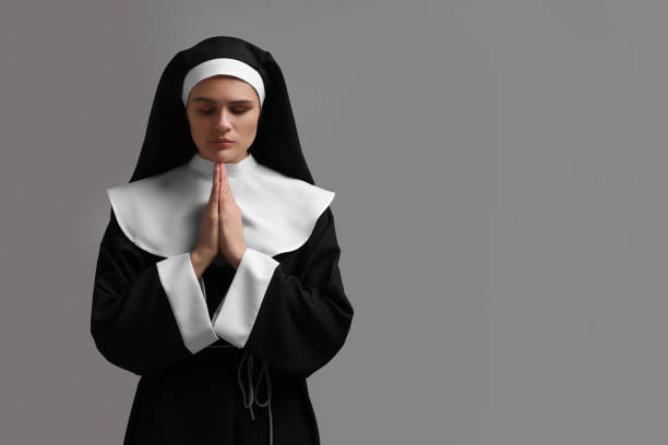 istock Nun with clasped hands praying to God on grey background. Space for text 1823062601