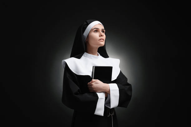 istock Young nun with Bible on black background 1823062614
