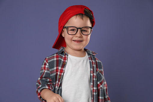 Cute little boy in glasses on purple background