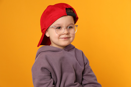 Cute little boy in glasses on orange background