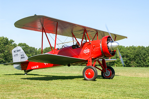 Side view of red airplane biplane with piston engine and propeller. Isolated on white background