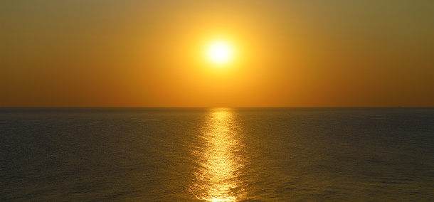 Orange sunset with sun path on surface of sea.