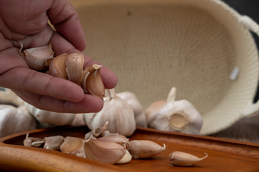 Male hands placing garlic on a wooden plate
