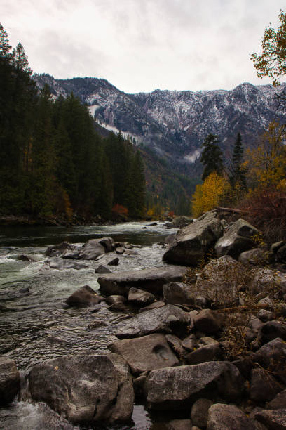 rapides d’eau vive à travers une rivière couverte de roches dans l’état de washington avec la chaîne de montagnes north cascades en arrière-plan avec un feuillage d’automne - north cascades national park cascade range river waterfall photos et images de collection