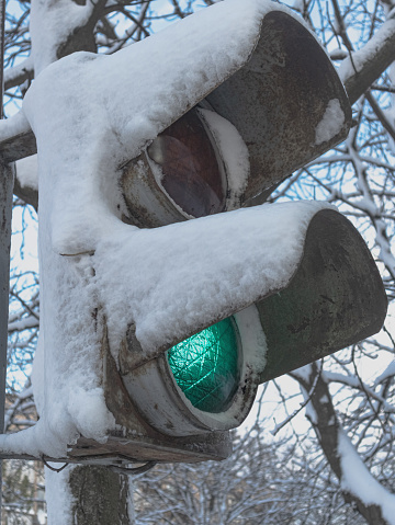 Old pedestrian traffic light in the snow. Permitting movement - green light