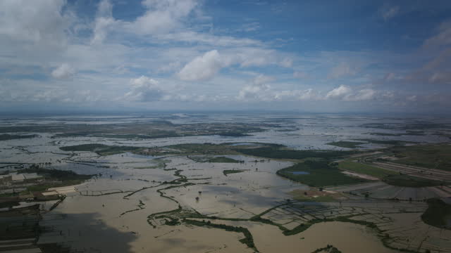 Aerial hyperlapse of daytime clouds flying over the flooded rice fields in rural Cambodia.