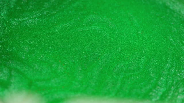 Abstract green emerald, gold ink spreads in waves, pained mix close-up. Rich light aqua green.