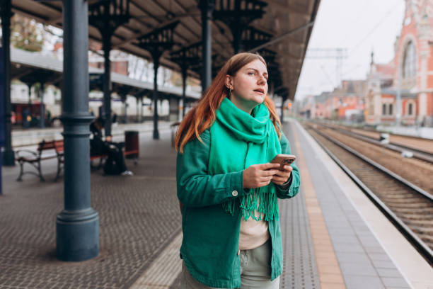 istock Young redhead woman waiting train with backpack and using smart phone. Railroad transport concept, Traveler. 30s Woman walking at railroad station platform. Travel to vacation by train 1823120950