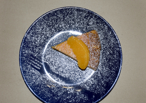 Pumpkin casserole with cottage cheese and tangerines on a blue plate sprinkled with powdered sugar. sour cream is served separately or poured on top. tasty and healthy food from autumn vegetables