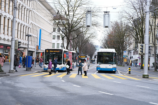 Lucerne, Switzerland - December 30, 2020: streets of city of Lucerne, pedestrians and blowing along pedestrian crossing through carriageway, road safety in Europe, concept of tourism, travel