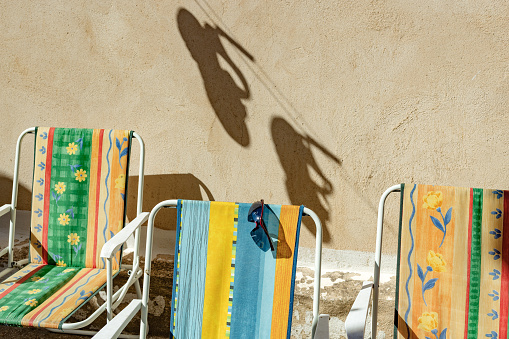 Castilla y León, Spain. Summer Scene: Colorful deck chairs, sunglasses, and the shade of sandals hanging on the clothesline to dry in the sun in a rural patio.
