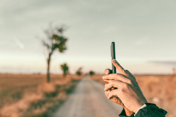 istock Man's hands taking a photo whit her mobile phone in a wilderness setting with few trees along a trail. 1823237580