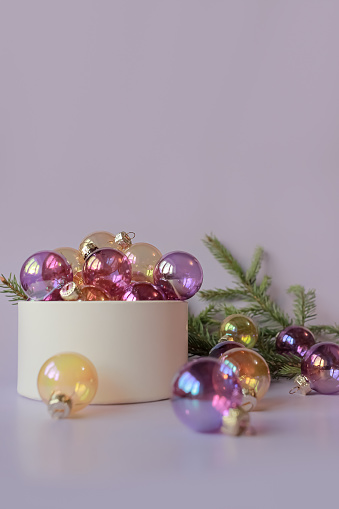 a lot of purple and yellow transparent glass christmas decoration baubles in box and near on lilac background. copy space