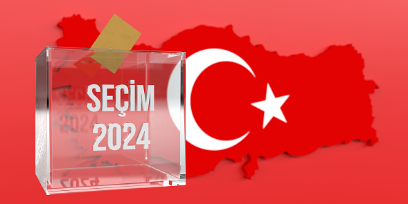 The yellow voting envelope is put into the glass ballot box. On the ballot box in front of Turkish flag, the 2024 local elections are written in Turkish. Large copy space on Turkish flag background.